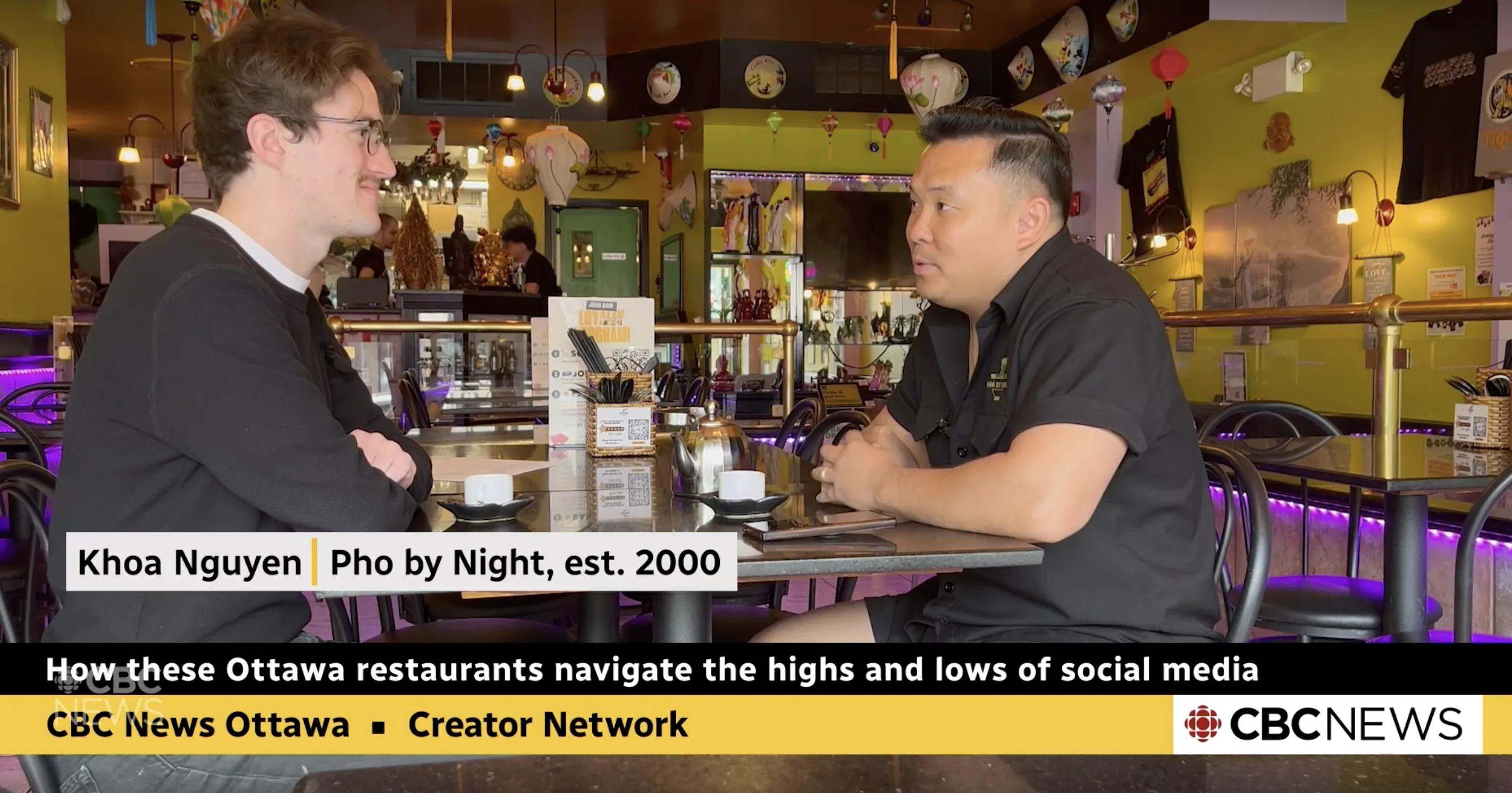 Pho By Night owner Khoa Nguyen speaking with a reporter inside the restaurant, featured by CBC News Ottawa